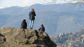 Three people on a rocky outcrop overlooking a town with mountains in the background.