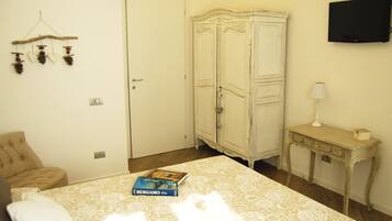 A bedroom with a bed, a wardrobe, a desk, and a television.