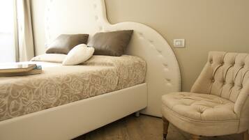 A bedroom with a bed, a chair, and a bedside table.