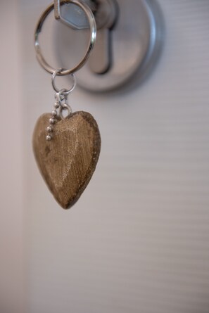 A keychain heart-shaped object with a metallic ring and a wooden texture. - Al San Lorenzo (Bergamo)
