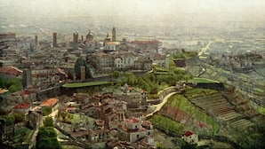 A historical cityscape with prominent buildings, including a large church with a dome and a bell tower, surrounded by smaller structures and green areas. - Al San Lorenzo (Bergamo)