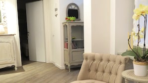 A room with a tufted armchair, a white cabinet, and a potted orchid. - Al San Lorenzo (Bergamo)