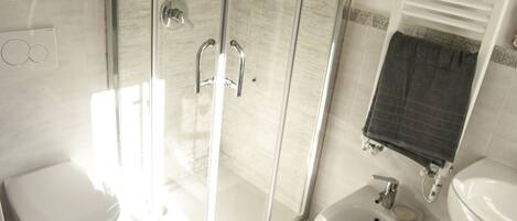 Un baño moderno con cabina de ducha de vidrio, inodoro, bidé y lavamanos.