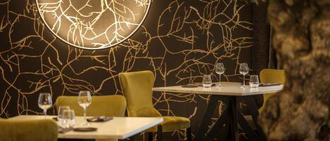 Interior de restaurante con un diseño de pared único, un elemento decorativo circular iluminado y una mesa preparada para dos comensales.