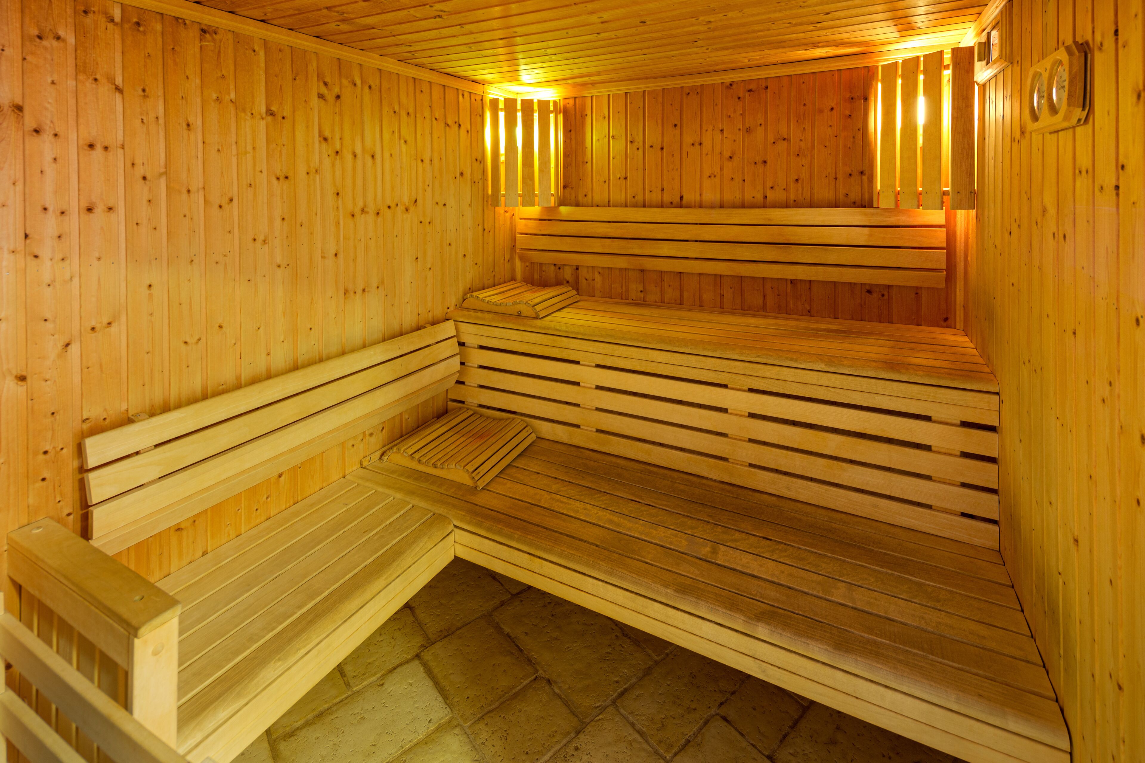 A sauna with wooden benches and benches, a tiled floor, and wooden walls.