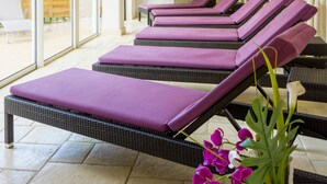 A spa area with reclining chairs and a white vase with purple flowers. - Logis Hôtel Restaurant Spa Parenthèse (Chille)