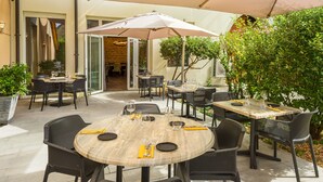 An outdoor patio area with round tables and chairs, umbrellas, and potted plants. - Logis Hôtel Restaurant Spa Parenthèse (Chille)