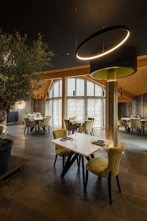 A spacious dining area with multiple tables and chairs, large windows, and a modern ceiling light fixture. - Logis Hôtel Restaurant Spa Parenthèse (Chille)