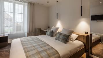 Una habitación de hotel moderna con una cama grande, un escritorio y un televisor en la pared.