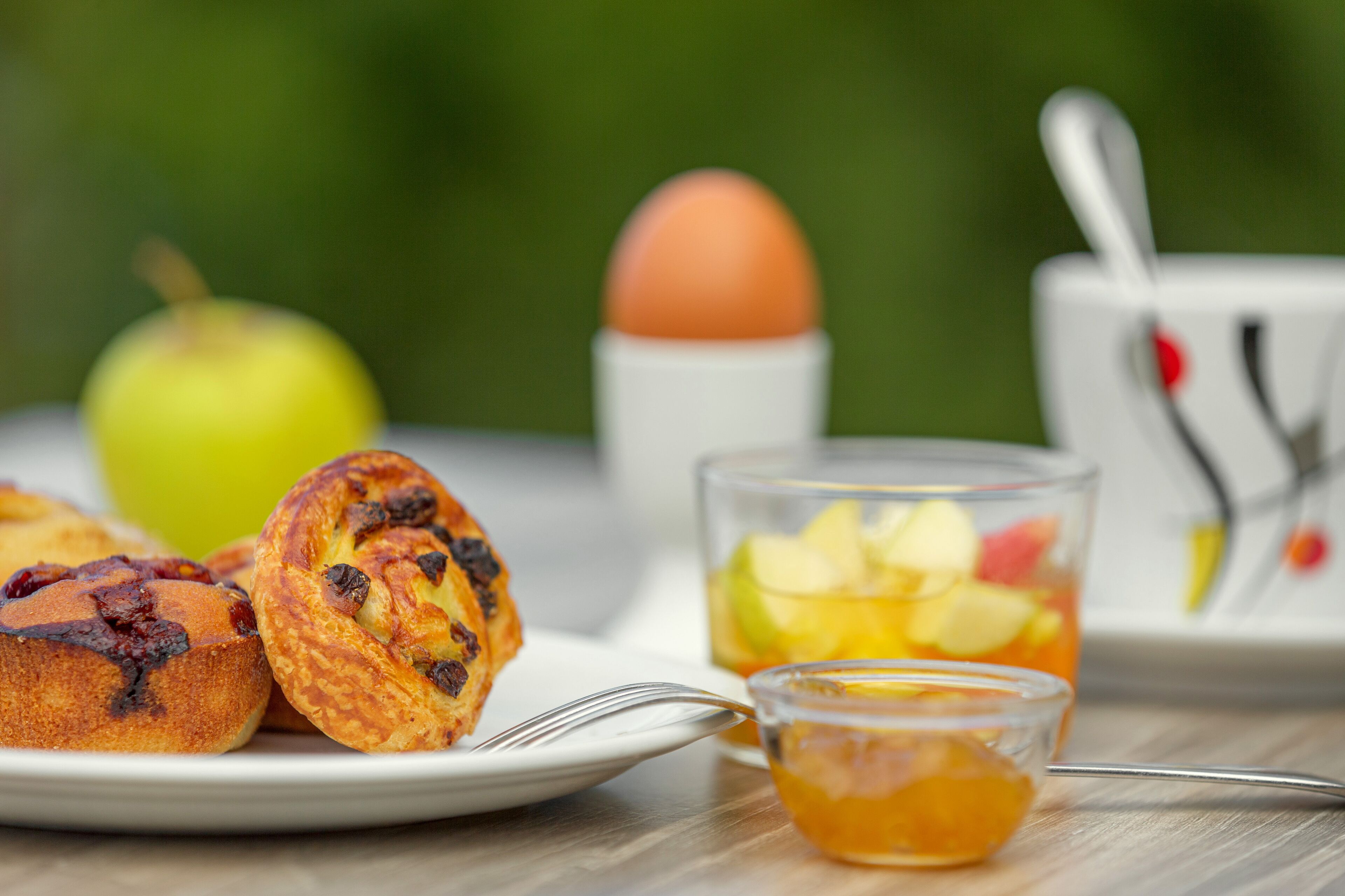 Desayuno con muffins, un vaso de jugo de manzana, una taza de té y un plato de comida.
