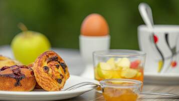 Desayuno con muffins, un vaso de jugo de manzana, una taza de té y un plato de comida.
