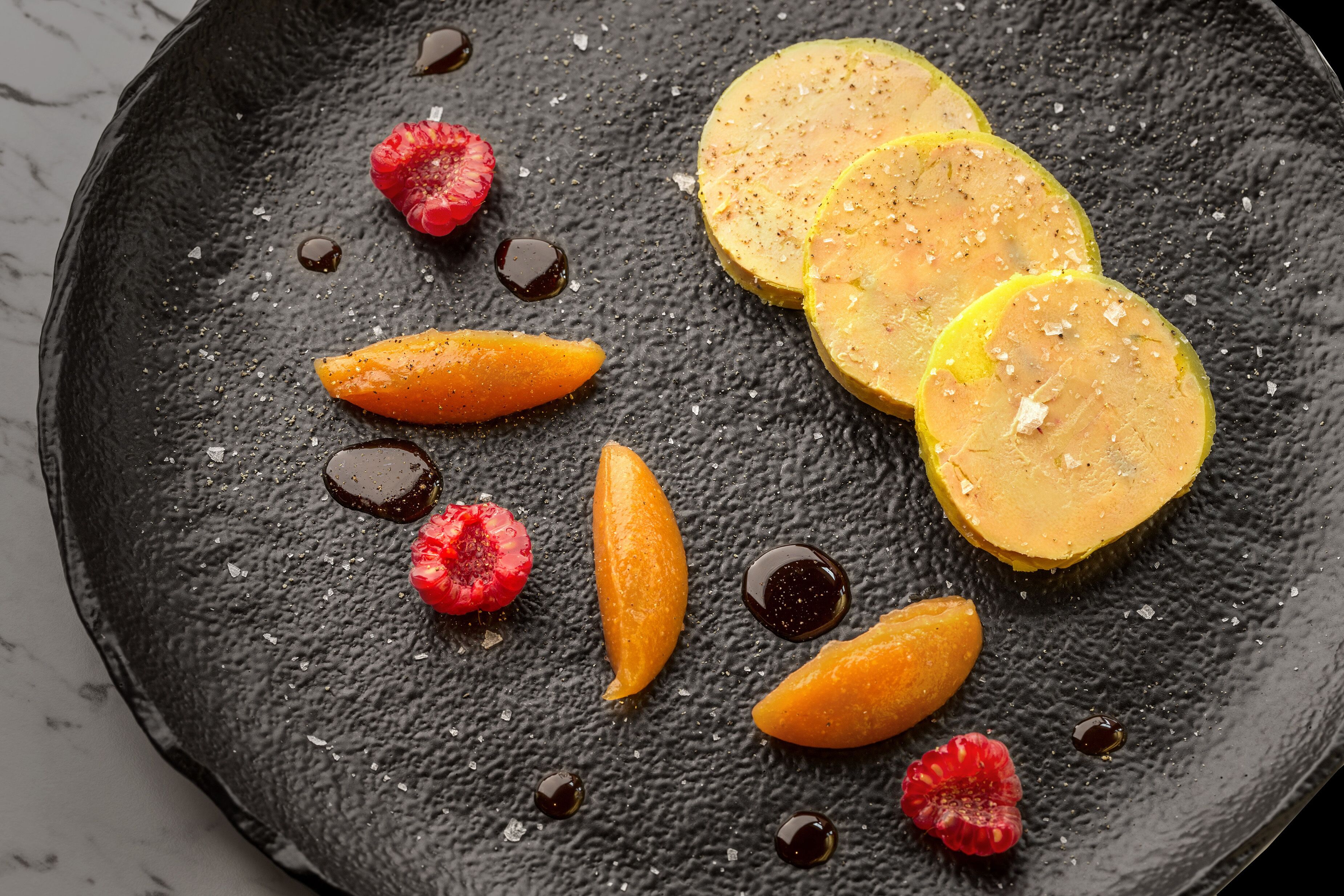 Un plato negro con fruta cortada y almíbar.