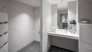 Un baño moderno con ducha, lavamanos y espejo.