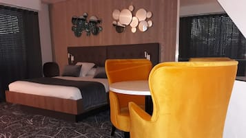 Een hotelkamer met een bed, een ronde tafel en twee gele stoelen.