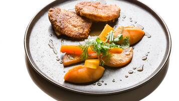 Une assiette contenant divers aliments, notamment des galettes de viande, des carottes et une garniture.
