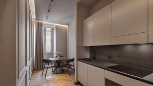 A modern kitchen with a herringbone floor, a round dining table, and a window with curtains. - Oriana Homèl Roma (Rome)