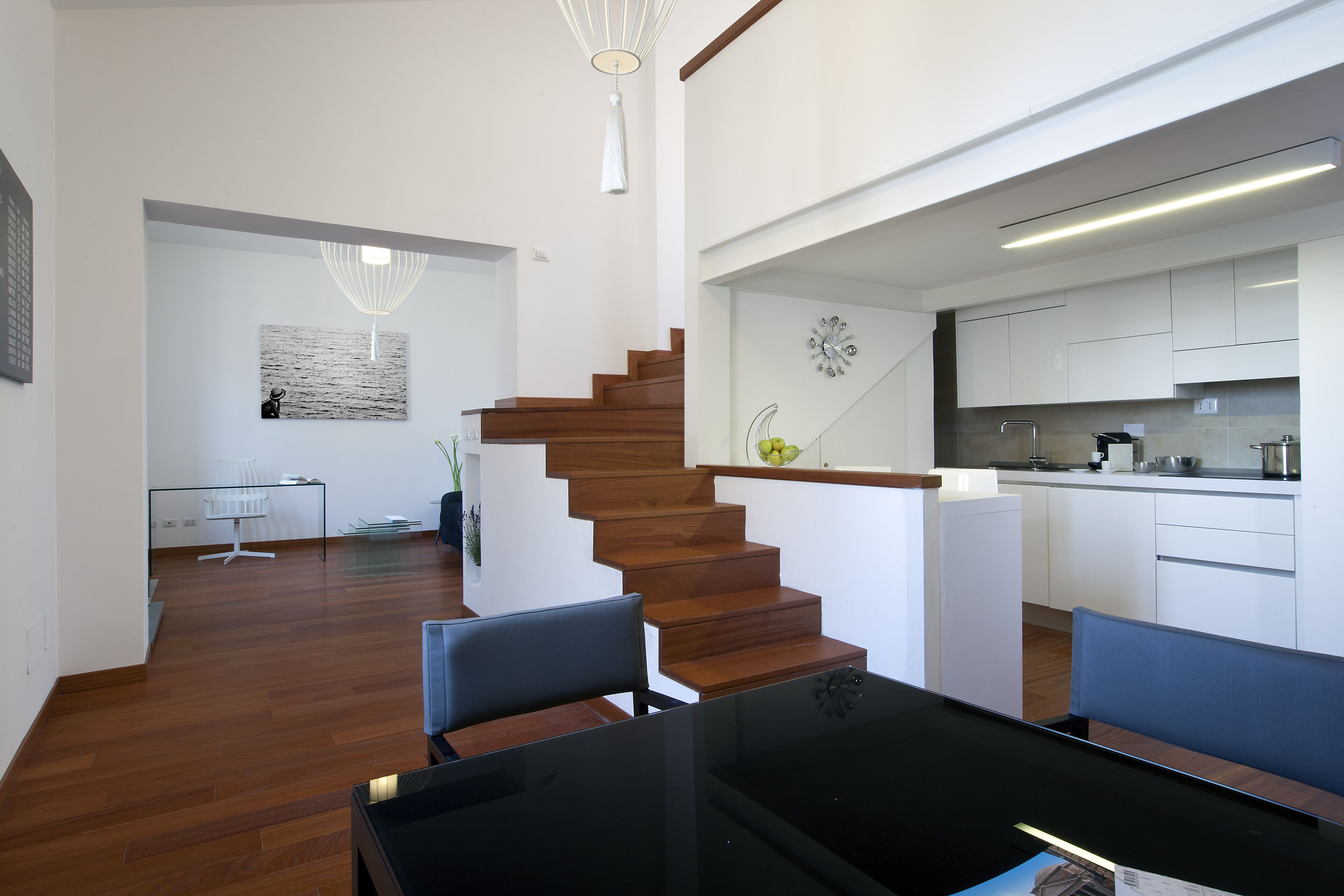 Un interior moderno con una escalera de madera, una zona de comedor y una cocina.