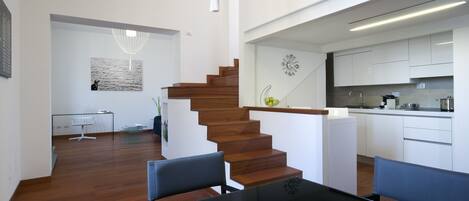 Un interior moderno con una escalera de madera, una zona de comedor y una cocina.