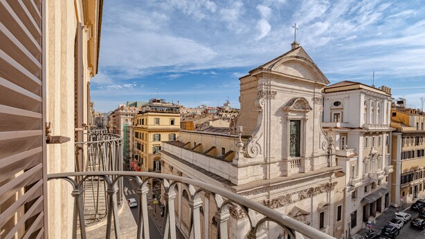 A view from a balcony overlooking a historic building with classical architecture, including a prominent dome and a cross on top. - Oriana Homèl Roma (Rome)