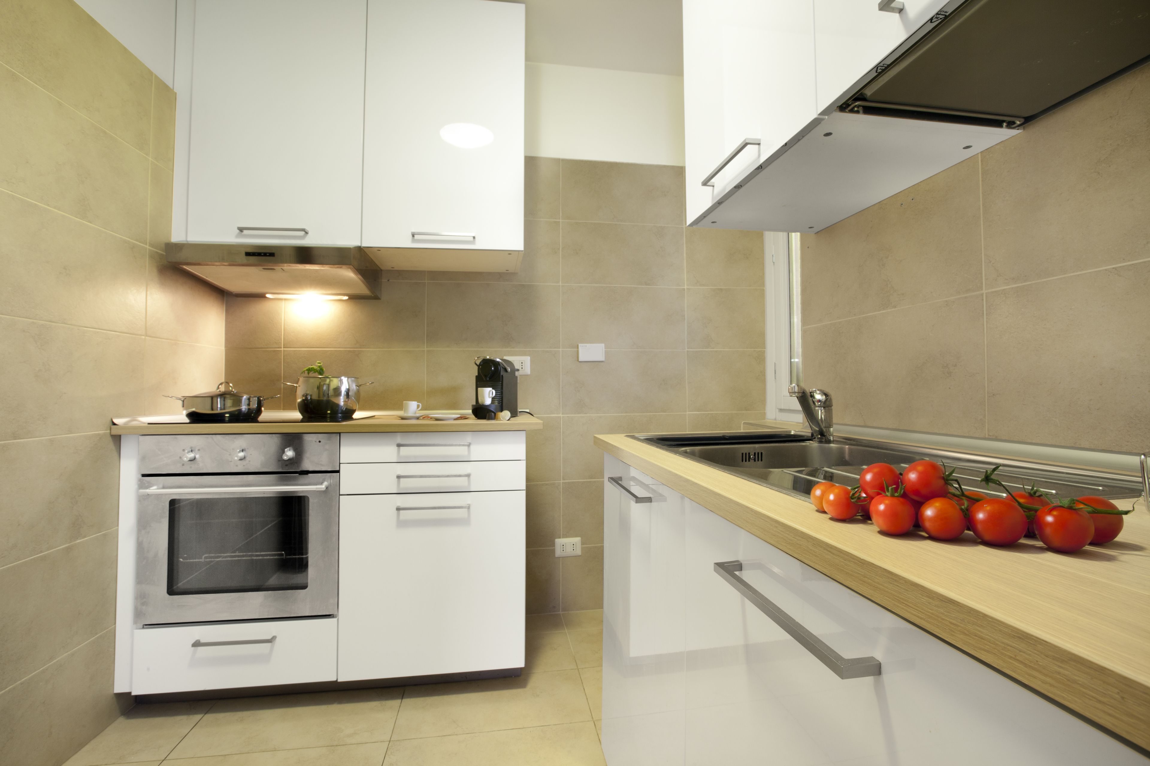 A modern kitchen with white cabinets, a stainless steel oven, and a wooden countertop.