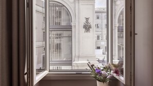 A corner room with a large window, a wooden side table with a vase of flowers, and a view of classical architecture. - Oriana Homèl Roma (Rome)