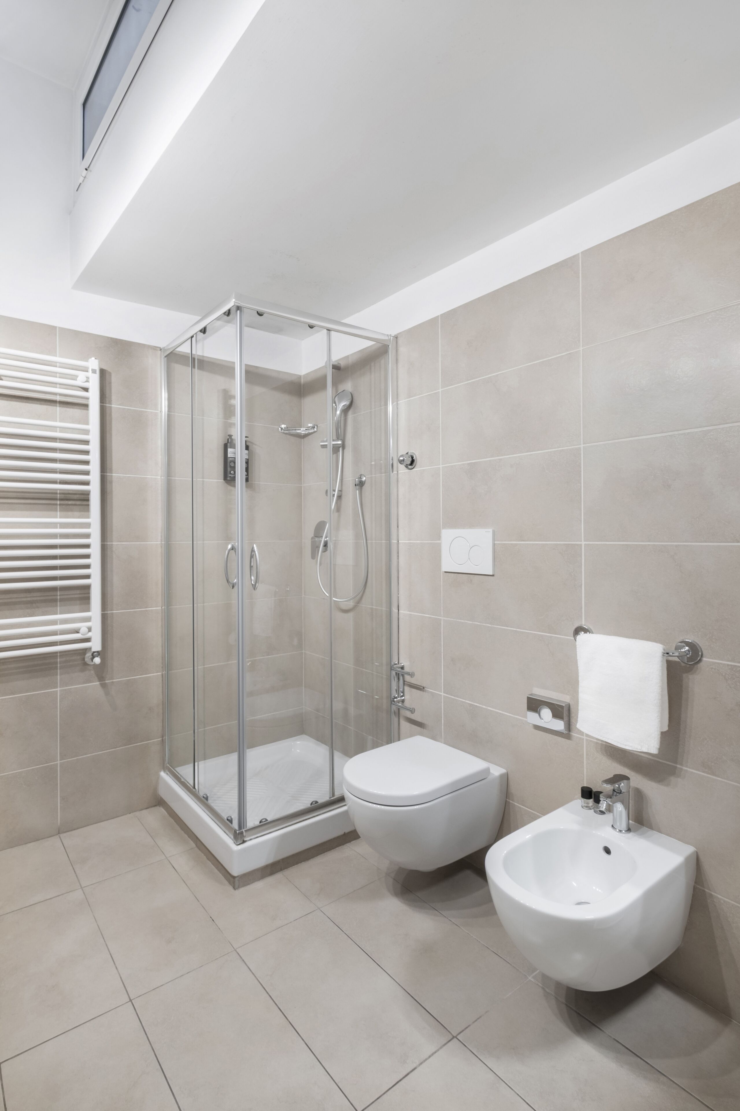 A modern bathroom with a glass-enclosed shower, a toilet, and a bidet.