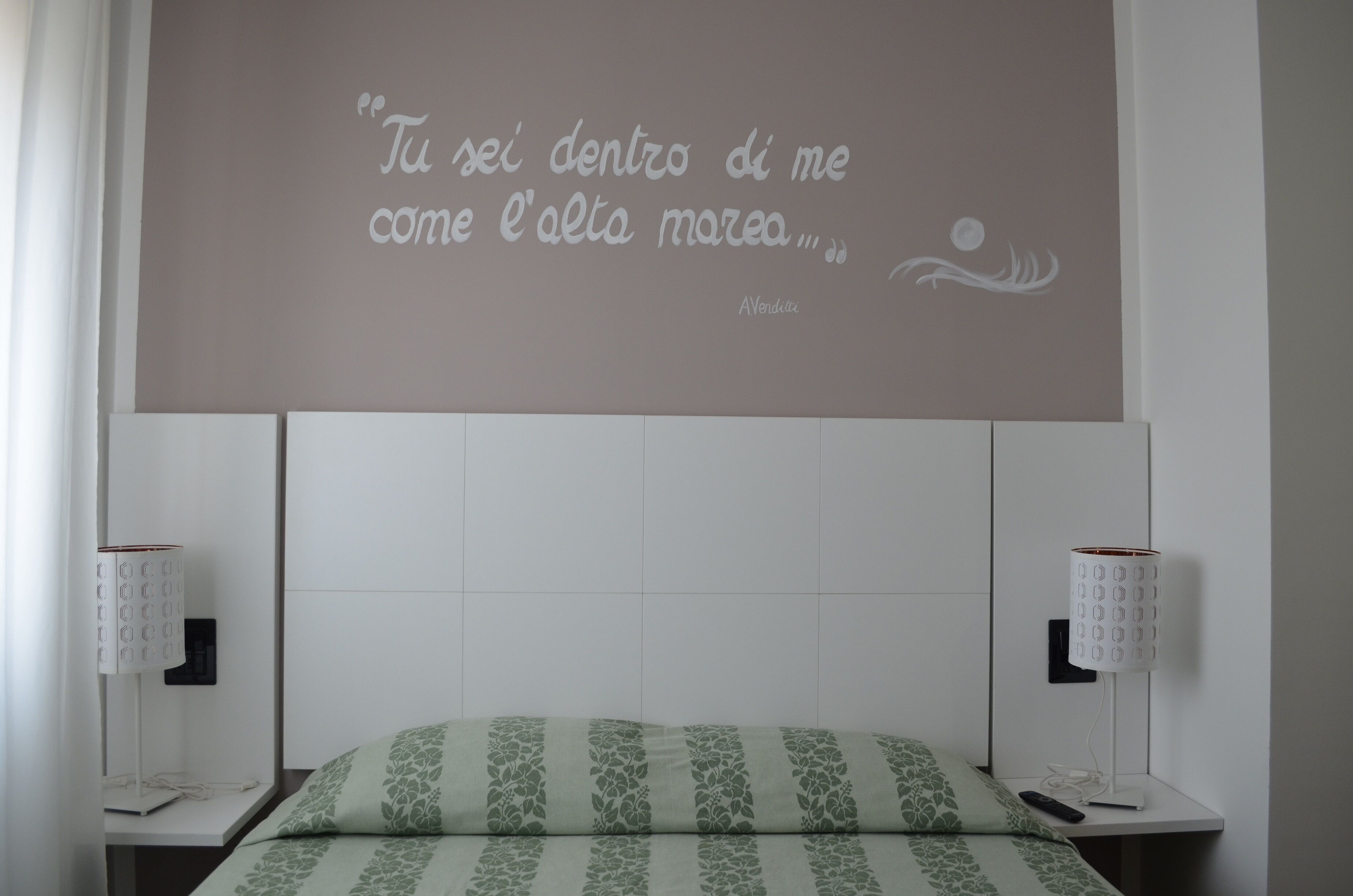 Une chambre à coucher avec un lit, une citation affichée sur le mur et deux lampes de chevet.