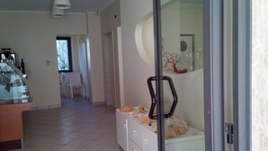 A modern kitchen with a dining area, a glass partition, and a view of the outdoors. - Hotel Sette Note (Silvi)