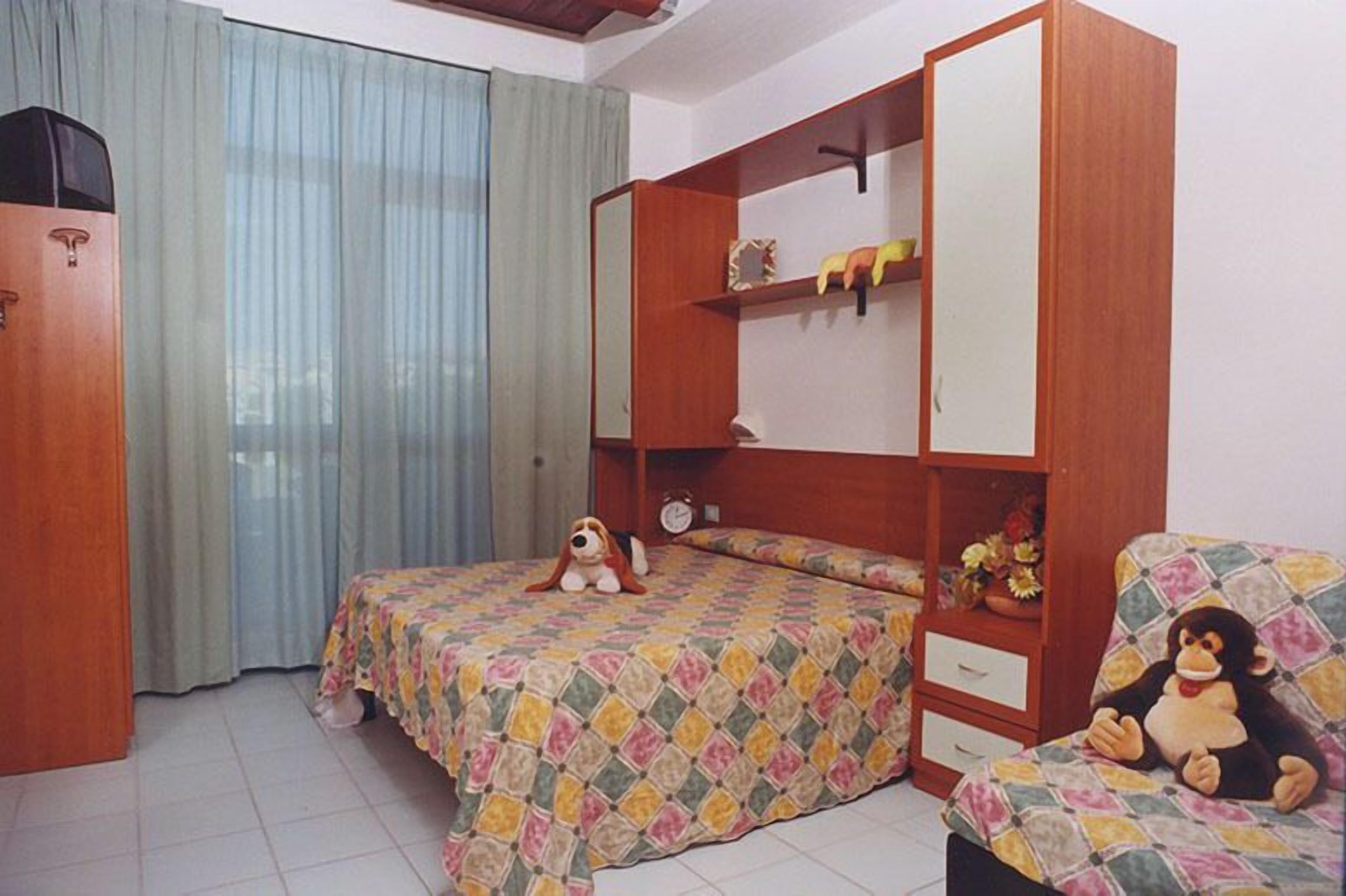 A bedroom with a bed, a wardrobe, a small table, and a chair.