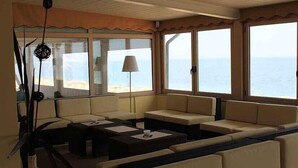 A room with a view of the sea, featuring a sofa set, a table, and a lamp. - Centro Vacanze De Angelis (Numana)