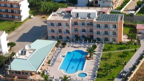 Un hotel con varias plantas, piscina y zona de estacionamiento.