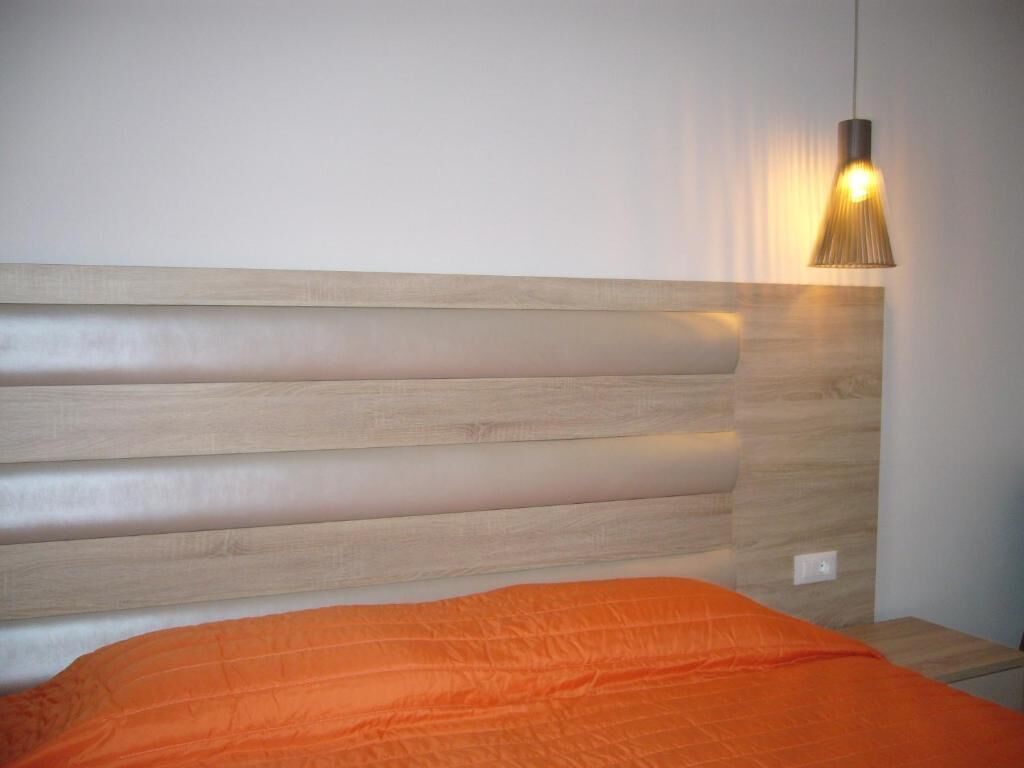 A bed with a wooden headboard and an orange blanket.
