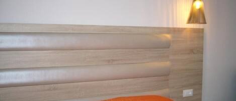 A bed with a wooden headboard and an orange blanket.