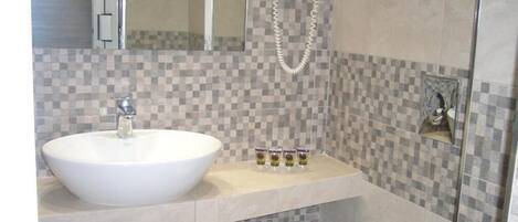 A bathroom with a white sink, a towel rack, and a shower head.
