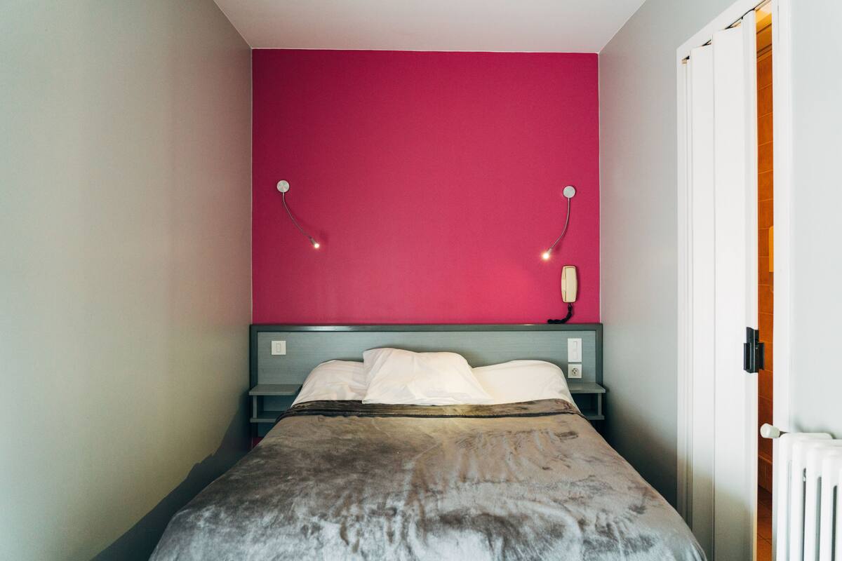 Ein Schlafzimmer mit einem Bett, einer rosa Wand und einer weißen Tür.