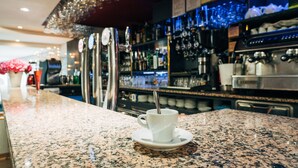 Zona de bar con encimera de granito, una taza blanca con cuchara y diverso equipo de bar.