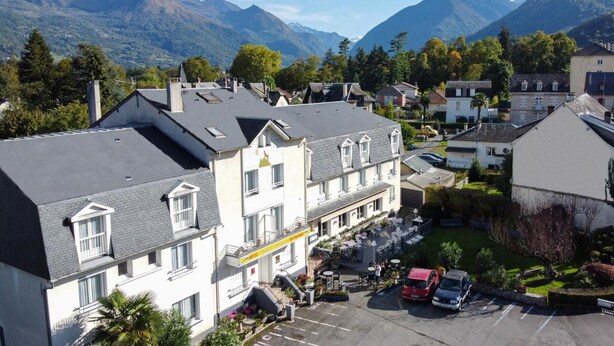 Un hotel con patio interior, varios pisos y montañas al fondo.