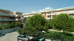 A residential building with multiple balconies, a parking area, and surrounding greenery. - Residence Azzurro (Massignano)