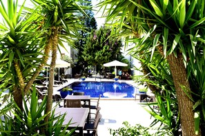 Una piscina al aire libre, sombrillas, sillones reclinables de piscina