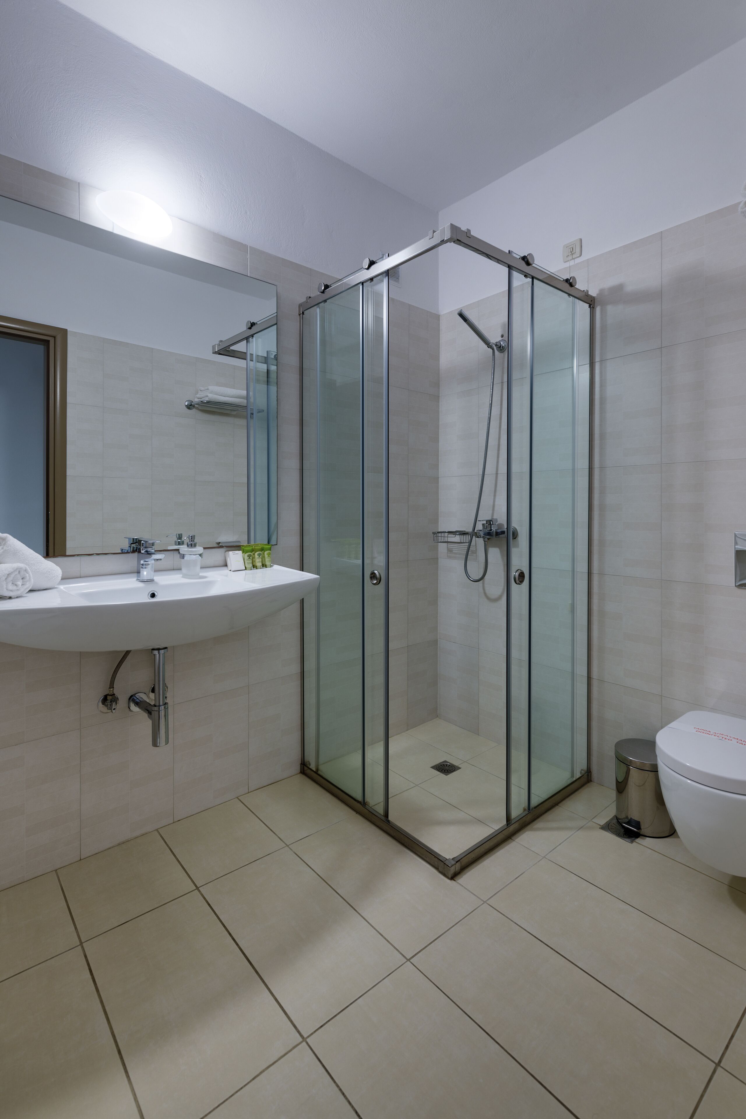 Un bagno moderno con doccia vetro, lavandino e specchio, e un water.