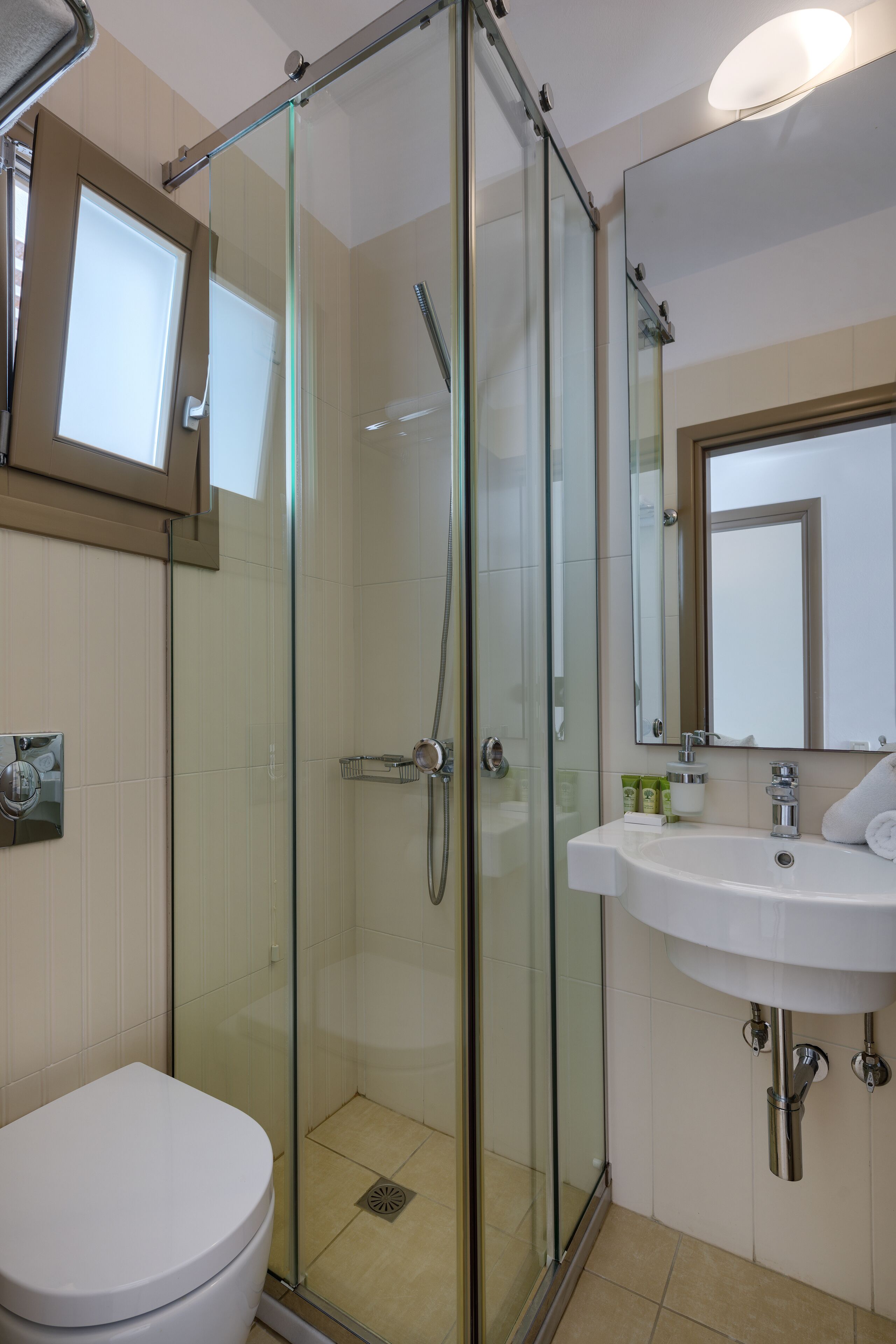 A bathroom with a glass-enclosed shower, a white sink, and a toilet.