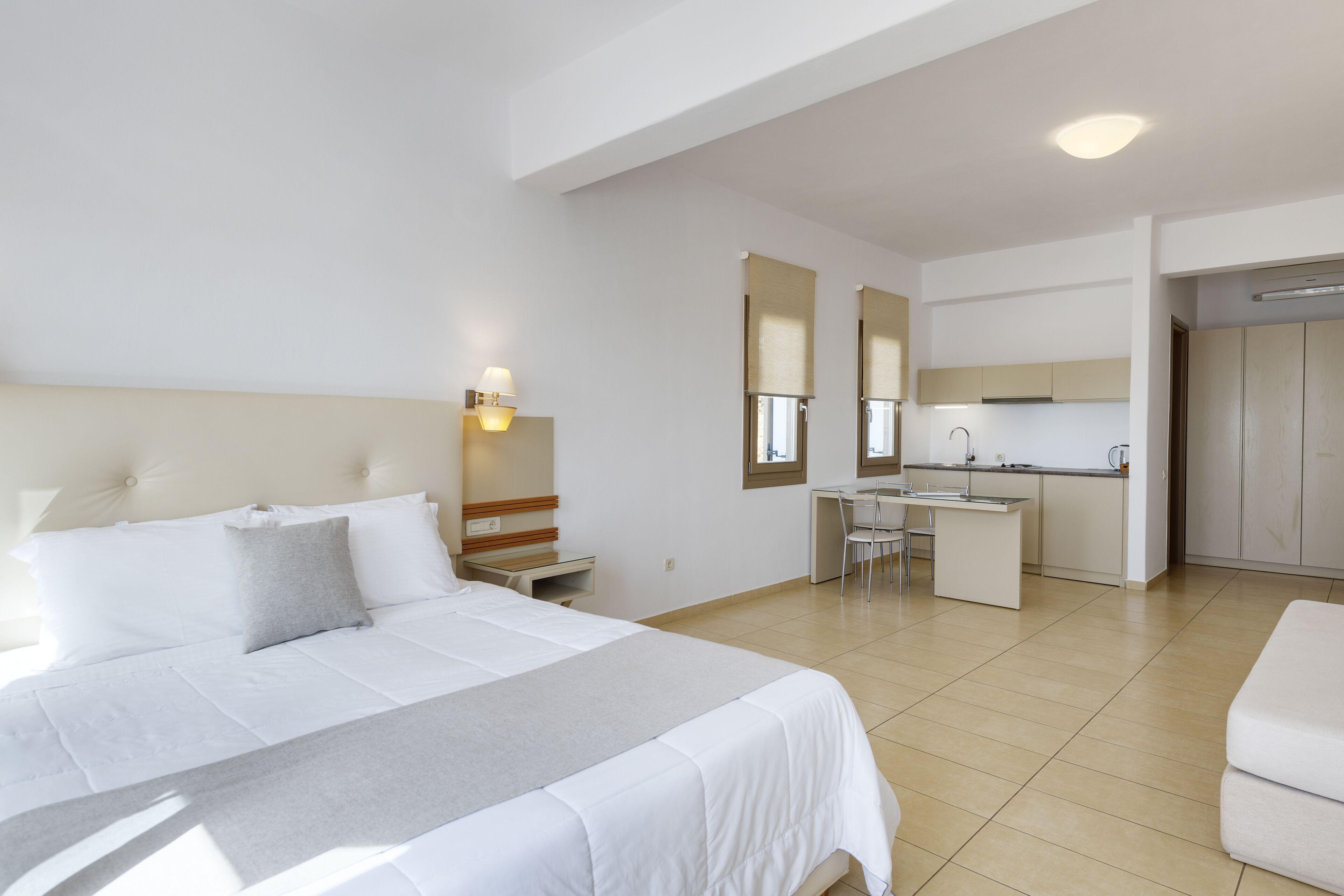 Una camera d'albergo con un letto, una scrivania e un angolo cottura.