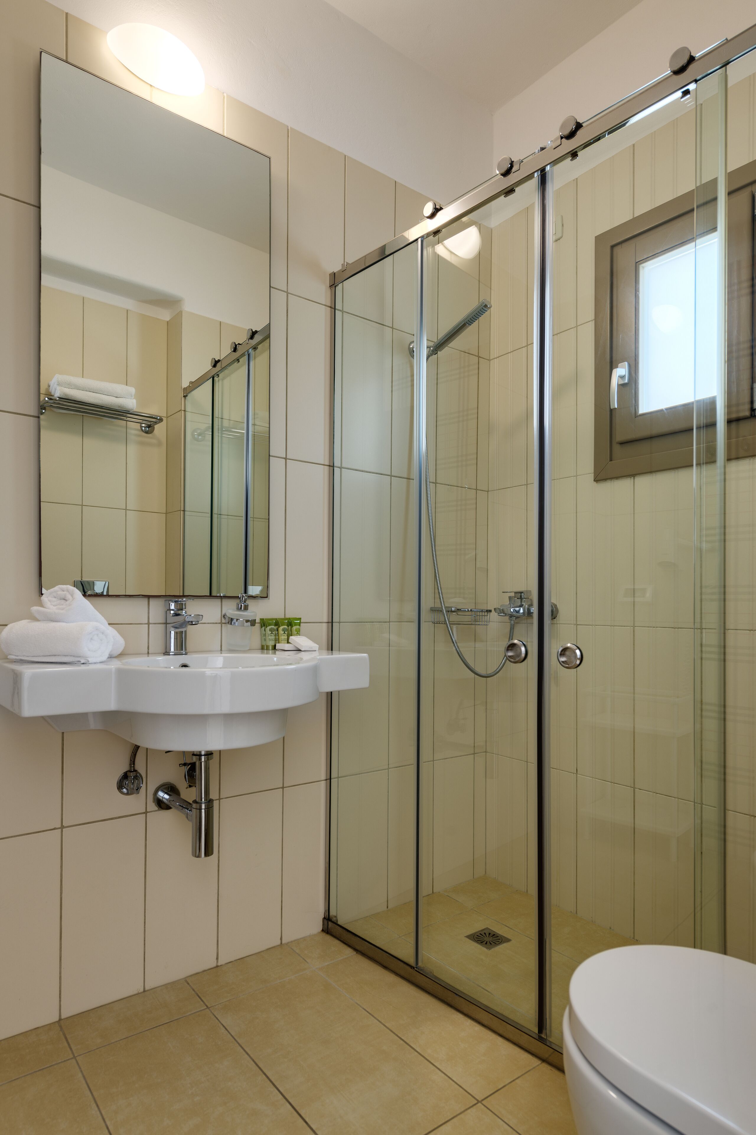 A modern bathroom with a glass-enclosed shower, a white sink, and a large mirror.