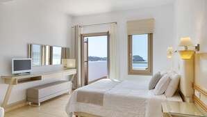 Quarto de hotel moderno com cama, escrivaninha, televisão e uma grande janela com vista para o mar.