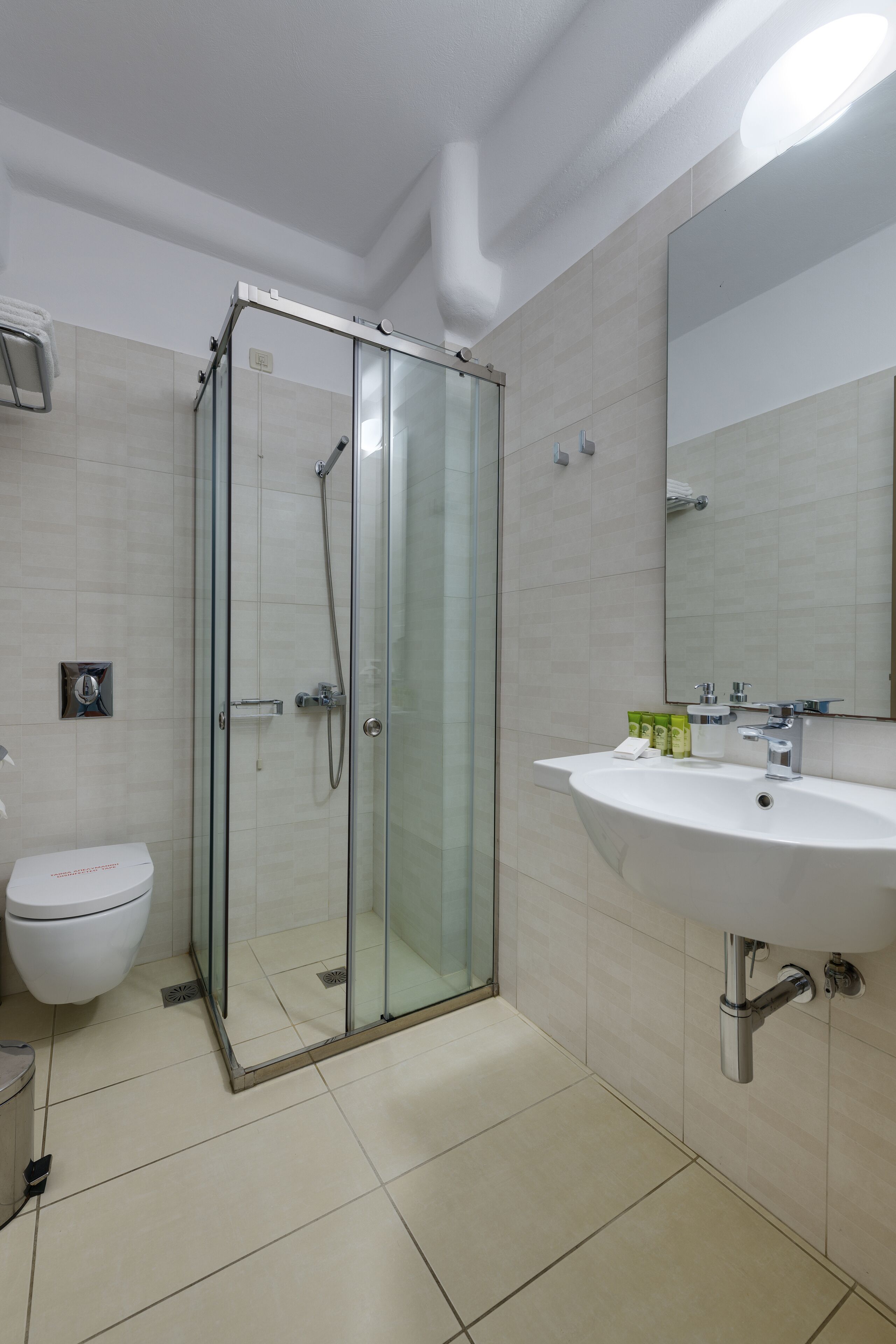 A modern bathroom with a glass-enclosed shower, a white sink, and a toilet.
