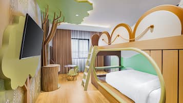 A children's room with a bunk bed, a TV, a desk, and a tree-themed wall design.