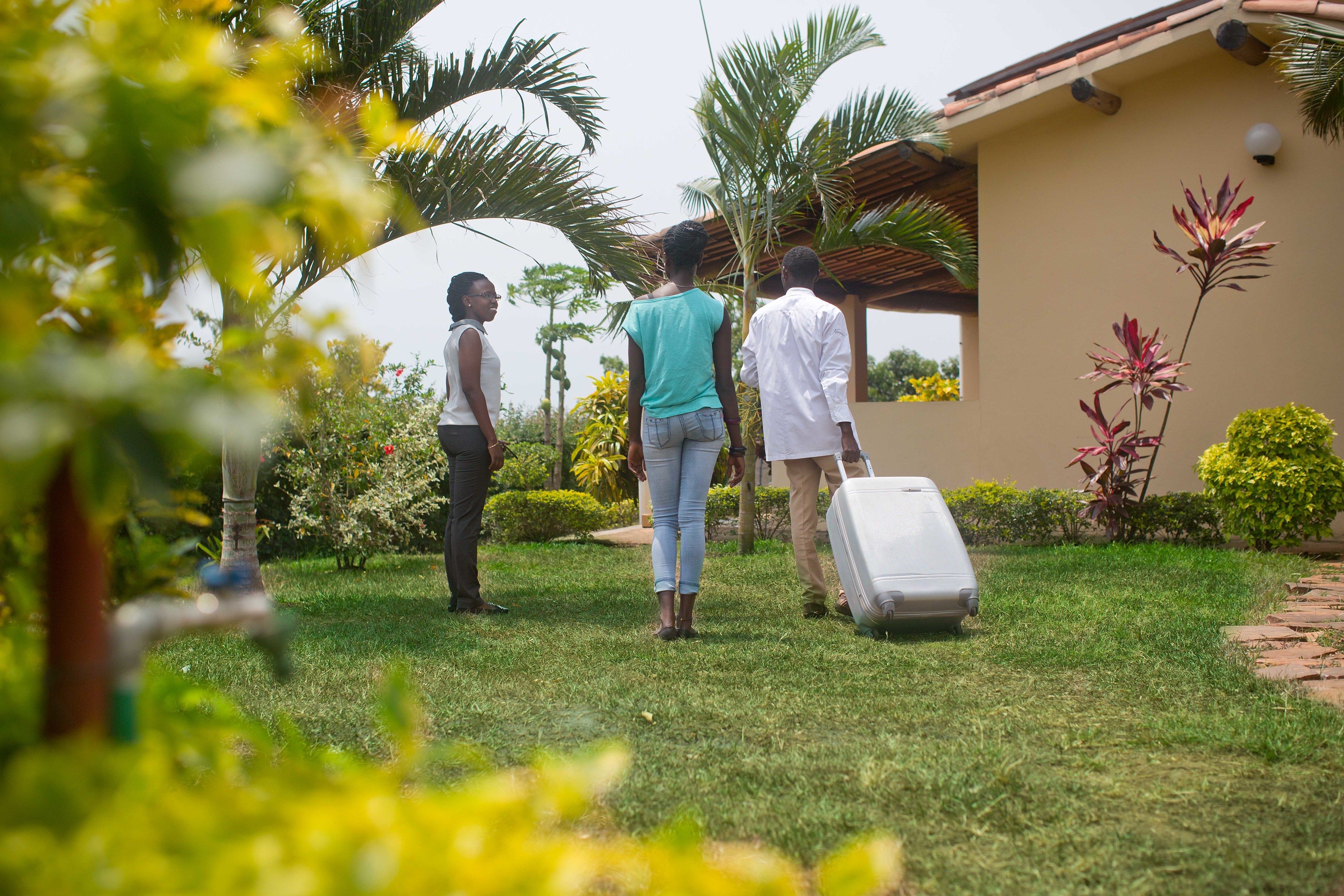 Three people standing in a garden with a house in the background.