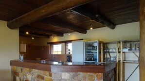 A stone bar area with a refrigerator and shelves, a sink, and a window. - Goodlife Residence (Bujumbura)