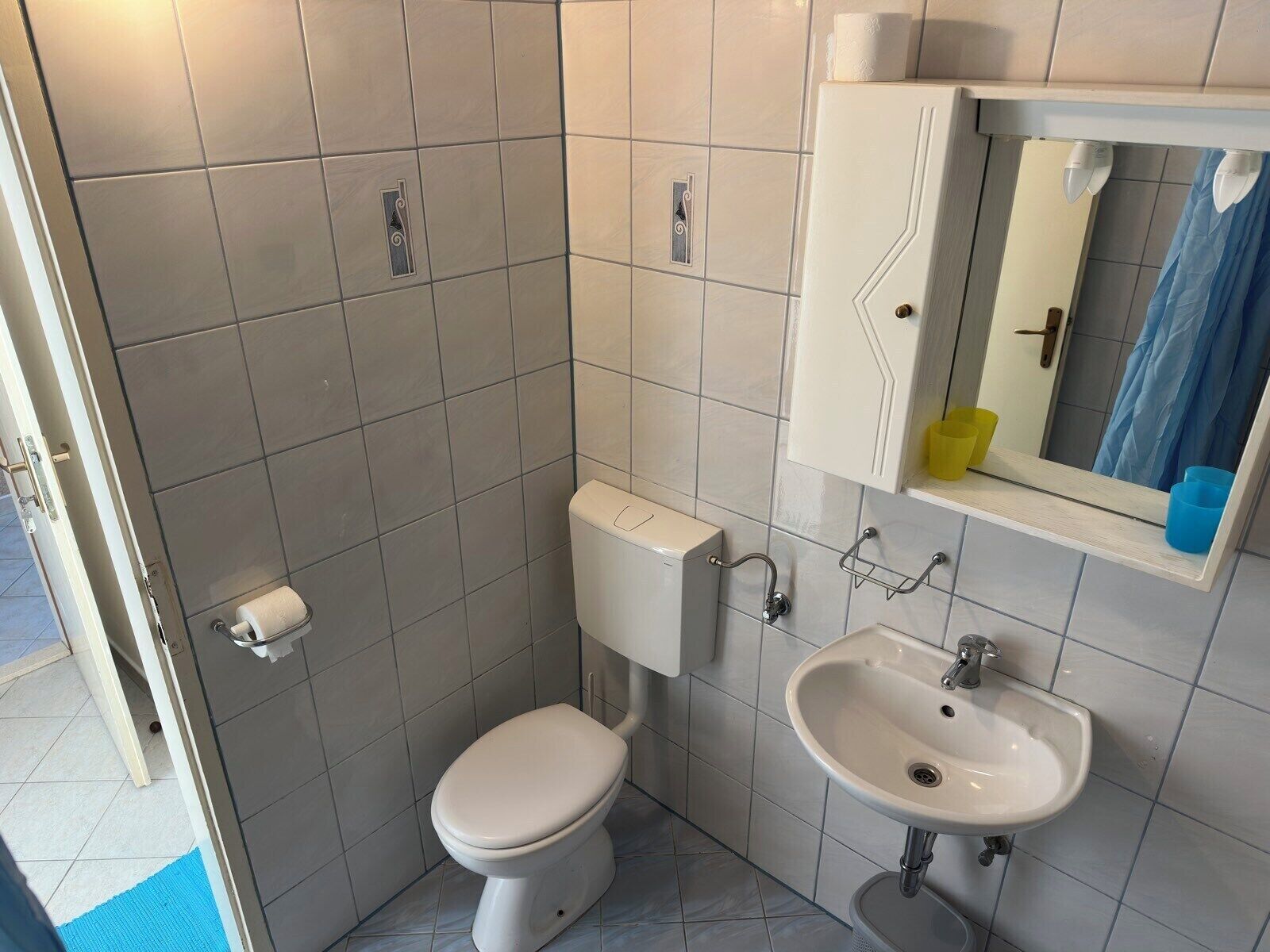Une petite salle de bain avec des toilettes, un lavabo et un miroir.