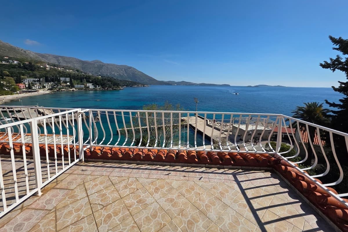 A terrace with a view of a coastal area, including a body of water and distant mountains.